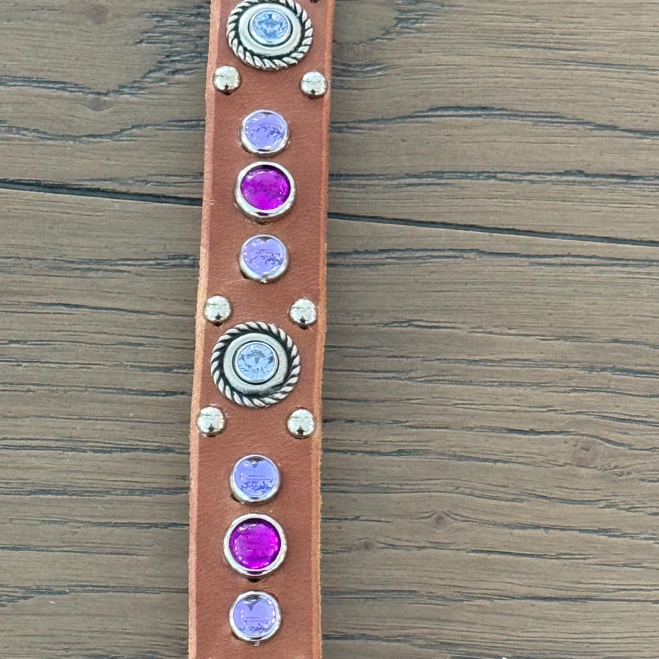 Leather strap with decorative Swarovski crystals and cabochons on a wooden surface