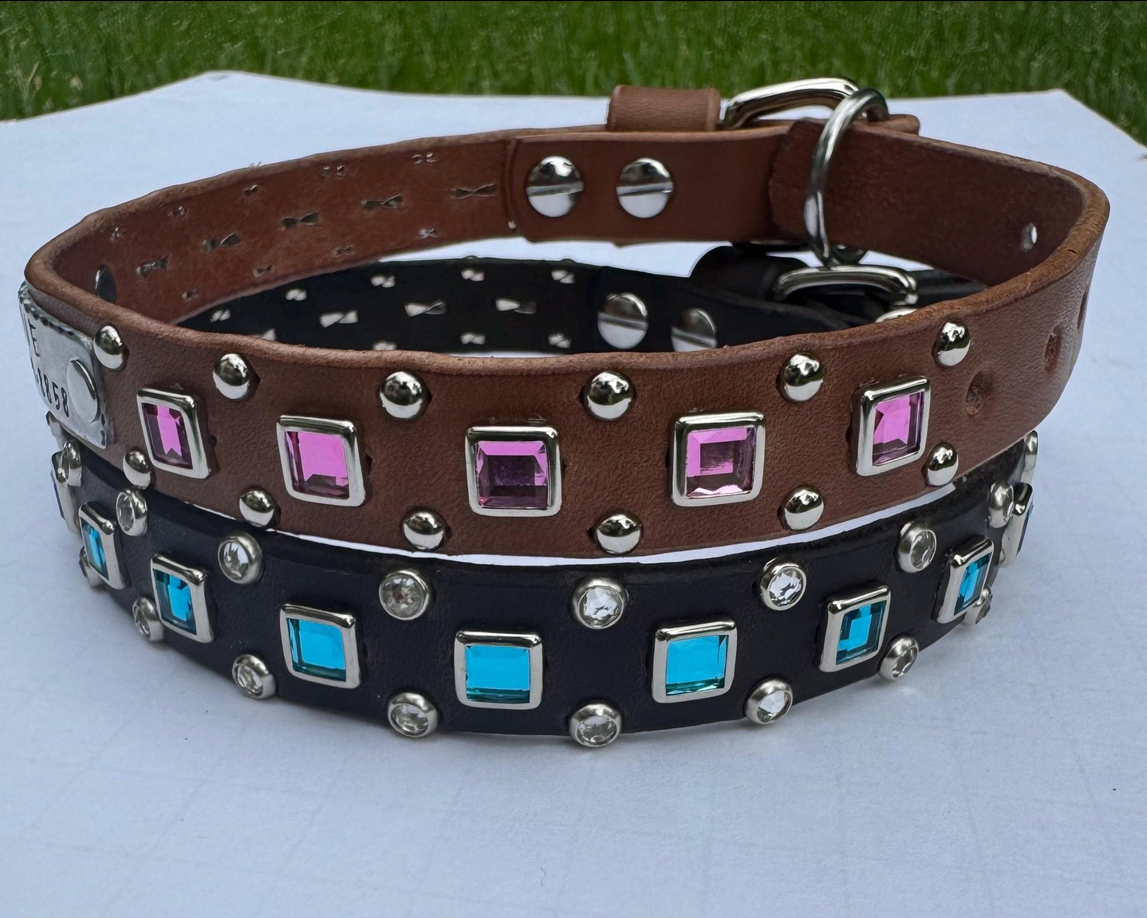 Two dog collars with decorative stones on a white surface.