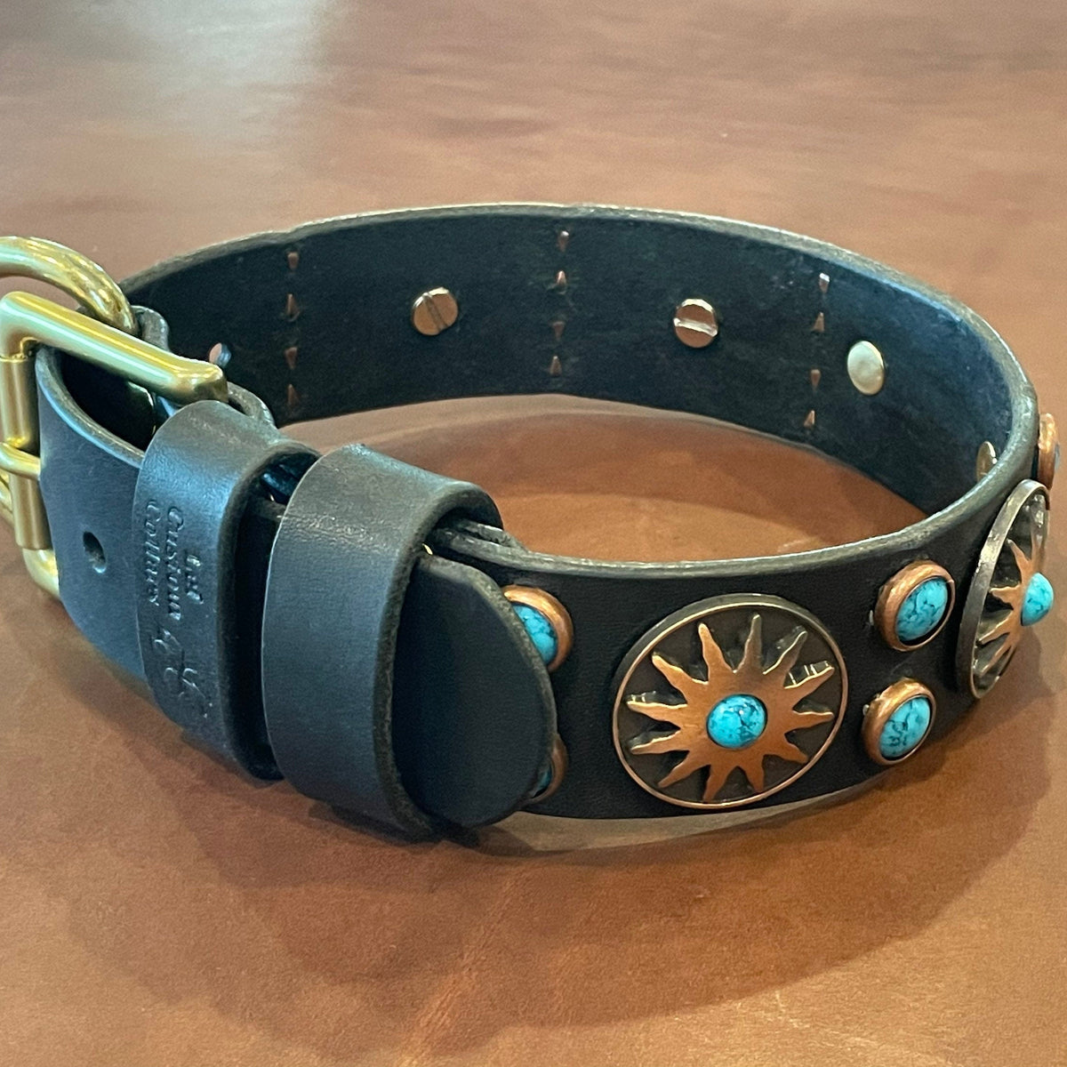 Western Native Sun leather dog collar with conchos and turquoise cabochons on a wooden surface